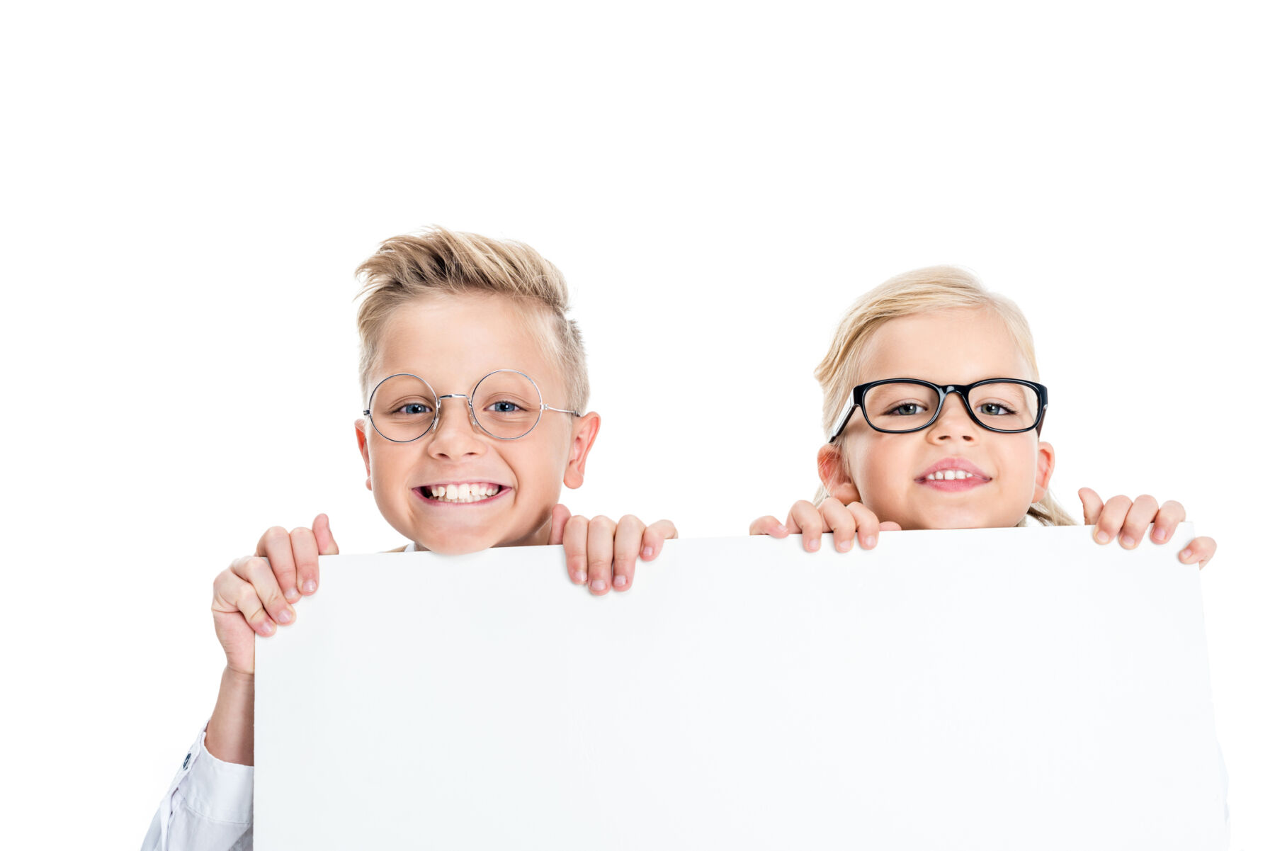 adorable little kids in eyeglasses holding blank banner and smiling at camera isolated on white